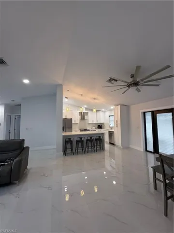 Living area featuring a ceiling fan and light marble finish floors