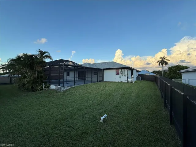 Rear view of property featuring a fenced backyard, a lanai, and a sunroom