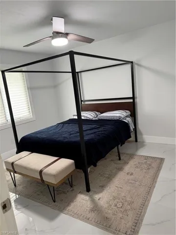 Bedroom with light marble finish floors and ceiling fan
