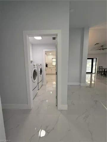 Laundry area with light marble finish floors and washing machine and dryer