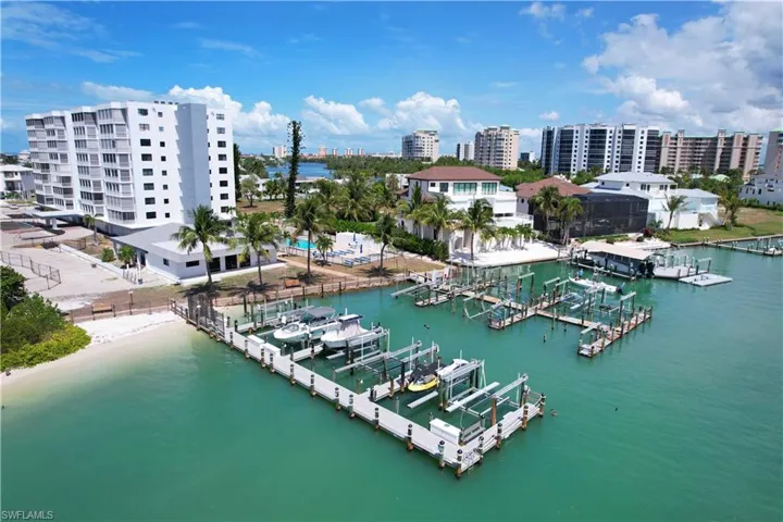 Waterfront property featuring a private beach, multiple boat slips, and a multi-story building