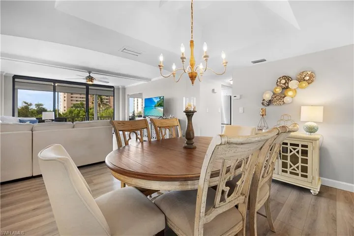 Dining area featuring wood-finish flooring, a tray ceiling, and a chandelier