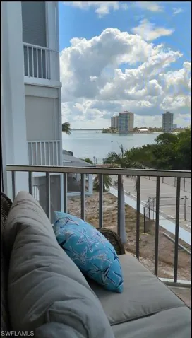 Balcony featuring water scenery with distant buildings and lush foliage