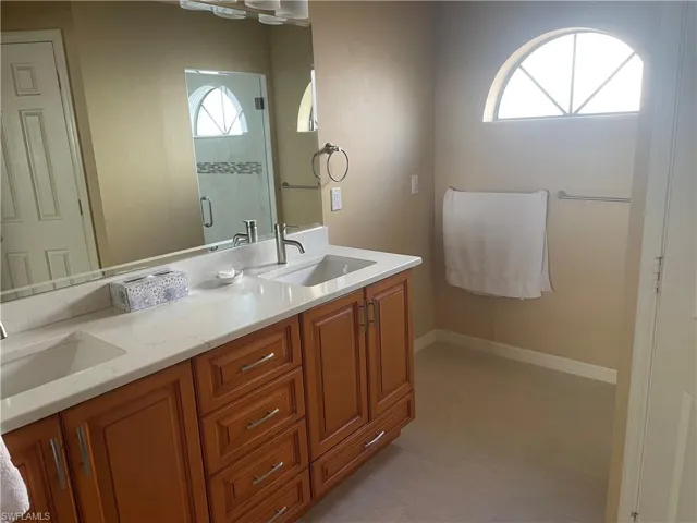 Bathroom featuring a dual vanity with light-toned countertops and wood-finish cabinetry