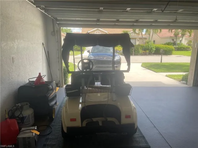 Garage interior featuring a concrete floor with a non-slip mat, painted stucco walls, and a roll-up garage door