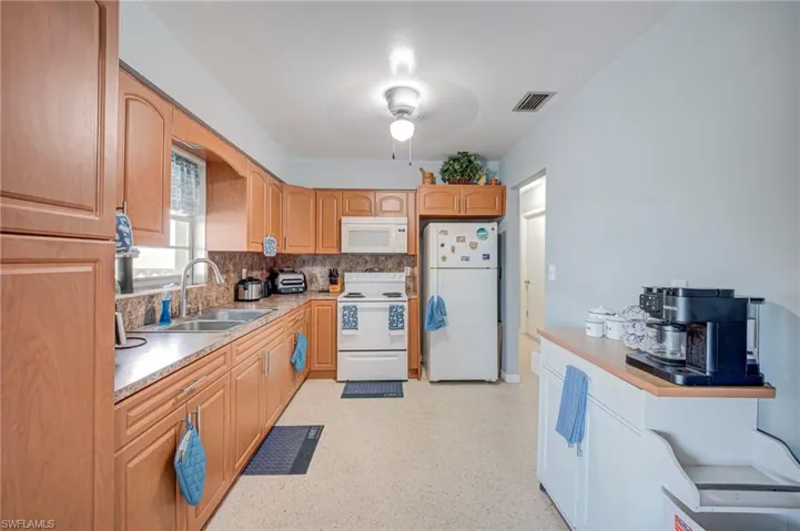 Kitchen featuring wood cabinetry, stone-finish countertops, stainless steel dual-basin sink, and a built-in over-the-range microwave