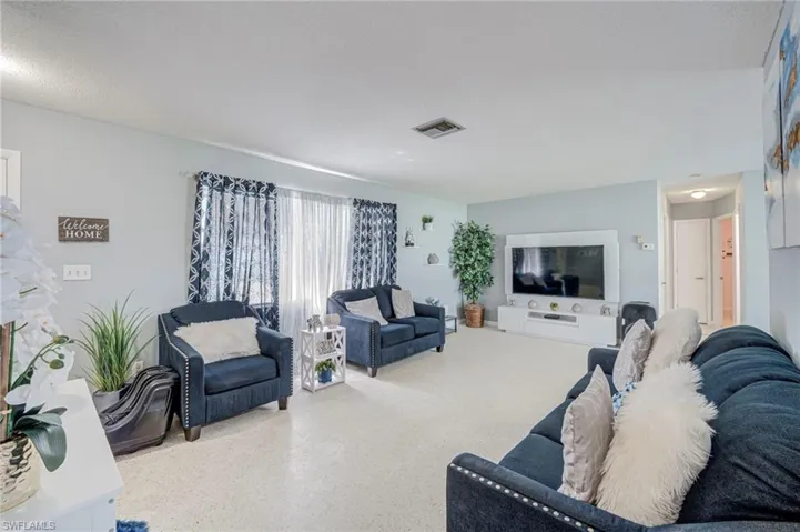 Living area featuring neutral flooring, expansive windows with custom drapery, and a large built-in media console