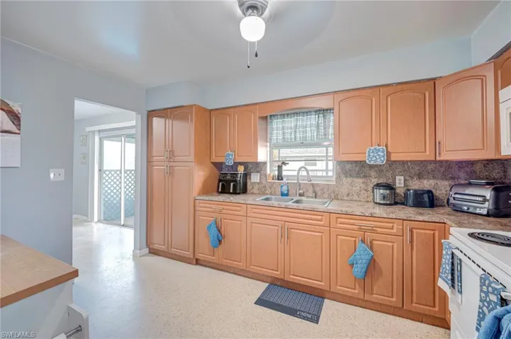Kitchen featuring wood cabinetry, laminate countertops, double-basin stainless steel sink, and a centralized ceiling-mounted light fixture