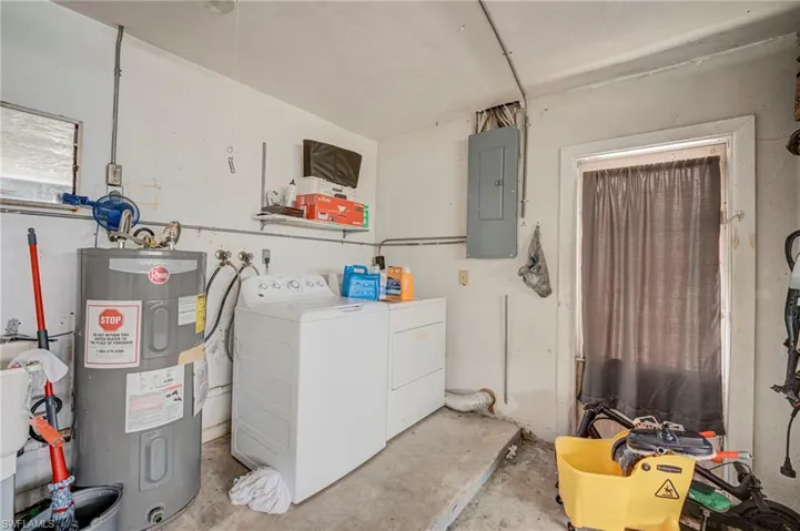 Utility area featuring a dedicated water heater, electrical panel, and laundry hookups with integrated shelving