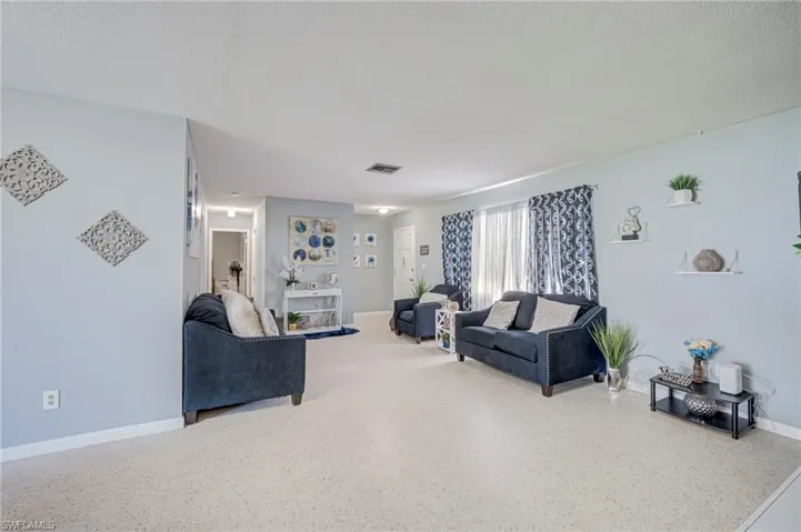 Open-concept interior space featuring light-toned flooring, wall-mounted display shelving, and recessed ceiling lighting