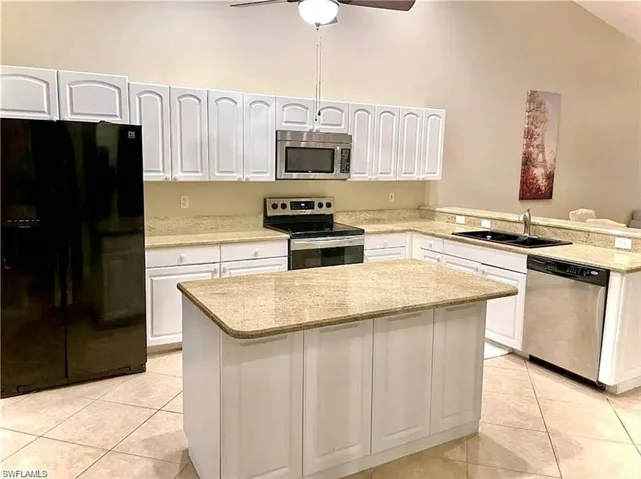 Kitchen with stainless steel appliances, light tile patterned floors, lofted ceiling, a peninsula, and white cabinetry