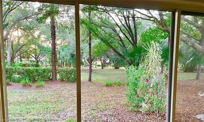 Expansive outdoor space featuring a screen enclosure, mature trees, and natural landscaping