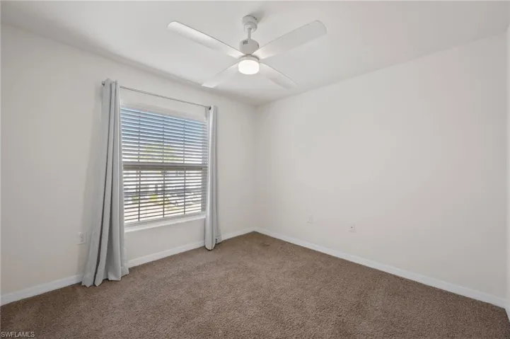 Carpeted empty room featuring ceiling fan and baseboards