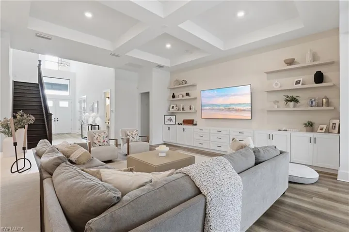 Living area with coffered ceiling, light wood-type flooring, and recessed lighting