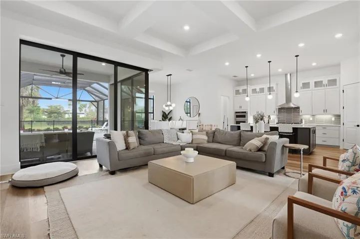 Living room with a sunroom, coffered ceiling, light wood-type flooring, and recessed lighting