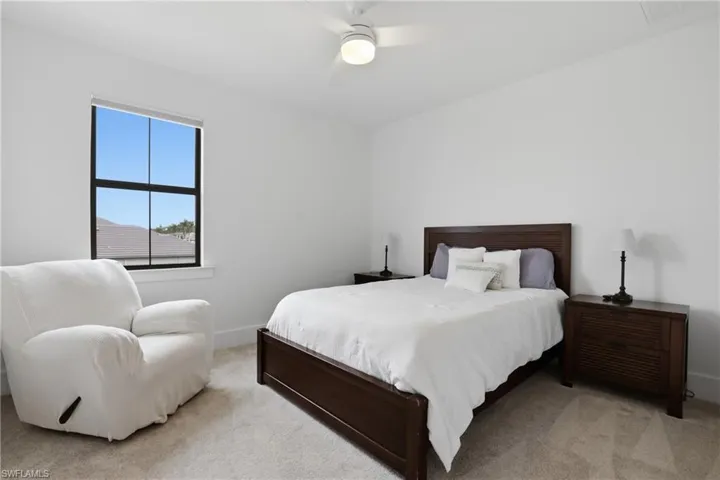 Carpeted bedroom featuring ceiling fan and baseboards