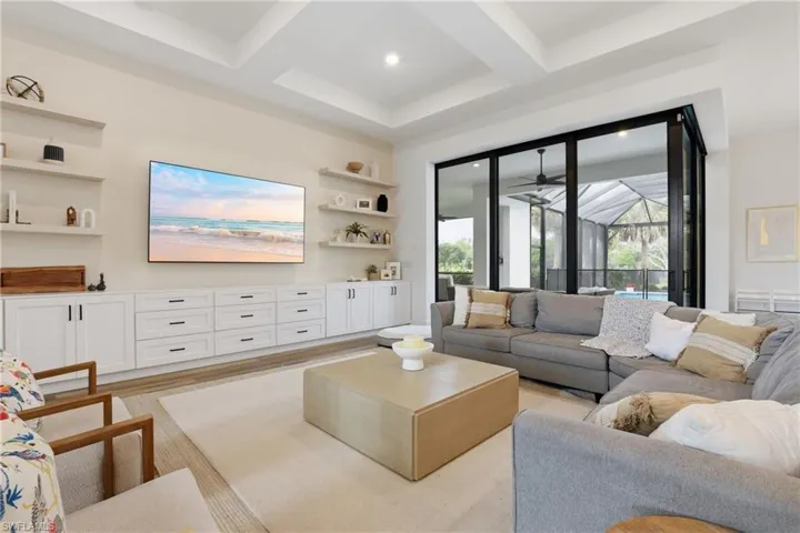 Living area featuring coffered ceiling, built in shelves, and light wood finished floors