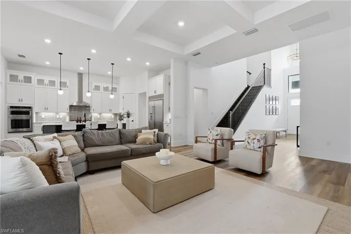 Living area with coffered ceiling, light wood-style flooring, and recessed lighting