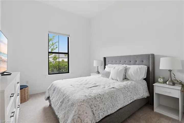Bedroom with light carpet and vaulted ceiling