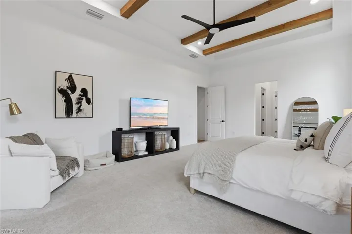 Carpeted bedroom featuring ceiling fan, recessed lighting, and a raised ceiling