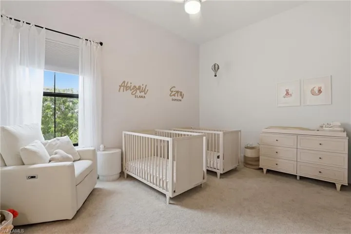 Bedroom with light carpet, a crib, and a ceiling fan