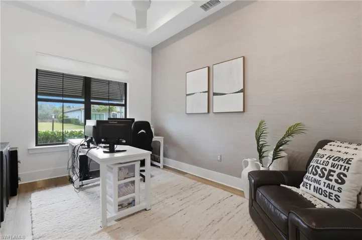 Office area with light wood-style floors and ceiling fan
