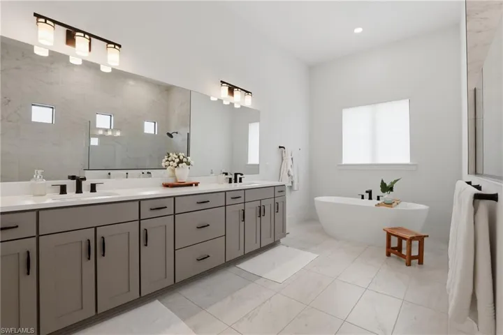 Bathroom featuring double vanity, a soaking tub, and tiled shower