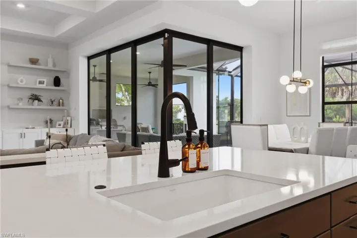 Kitchen featuring open floor plan, suspended lighting, light stone countertops, and dark wood finish cabinets