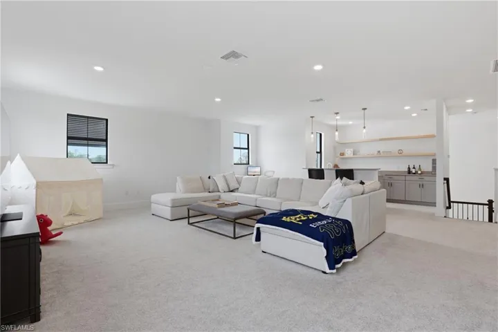 Living area with light carpet and recessed lighting