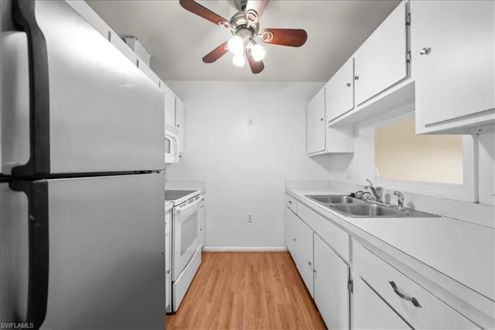 Kitchen featuring white appliances, white cabinetry, light countertops, and light wood-type flooring