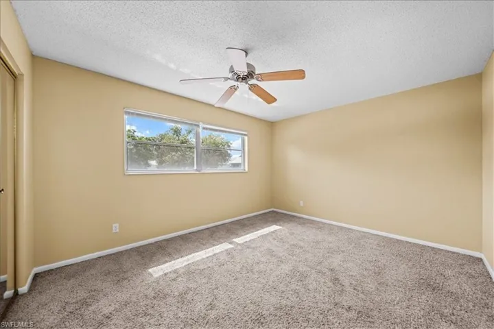 Empty room with carpet flooring, a textured ceiling, and ceiling fan
