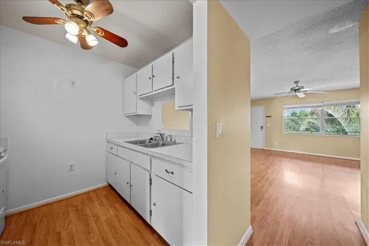 Kitchen featuring ceiling fan, white cabinets, light wood finished floors, and light countertops