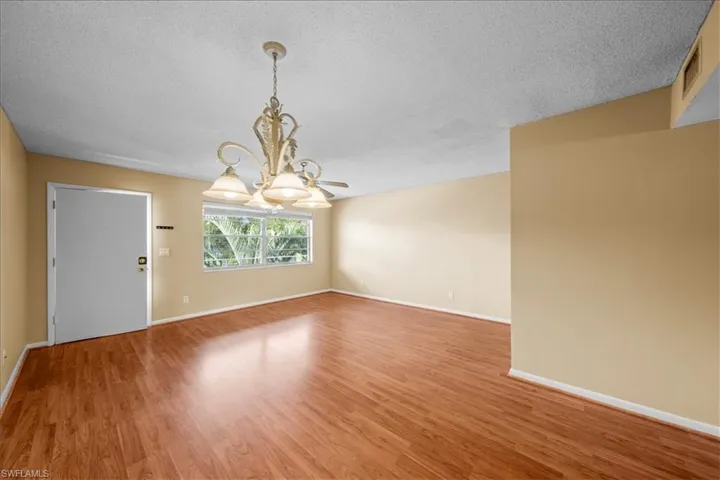 Unfurnished room with a textured ceiling, light wood-style flooring, and a chandelier