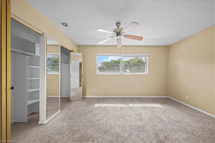 Unfurnished bedroom featuring carpet flooring, a ceiling fan, and a textured ceiling