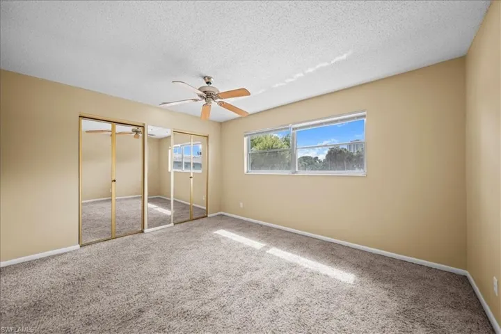 Unfurnished bedroom featuring two closets, carpet floors, ceiling fan, and a textured ceiling