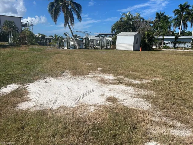 View of grassy yard with boat lift and a storage unit