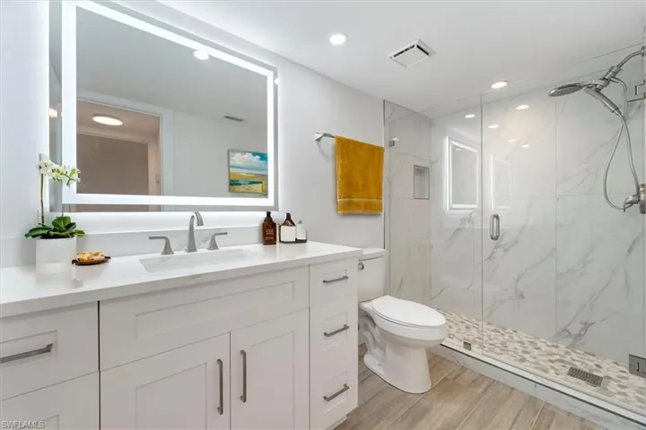 100 Estero BLVD #633_Virtually Staged - Bathroom with a marble finish shower, vanity, toilet, wood finished floors, and recessed lighting