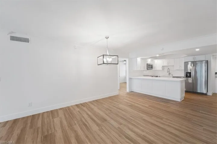 100 Estero BLVD #633_Kitchen featuring stainless steel appliances, light countertops, a peninsula, tasteful backsplash, and light wood-type flooring