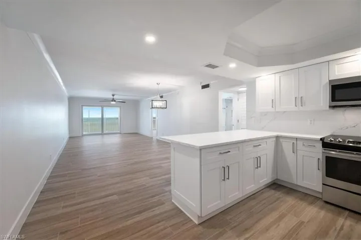 100 Estero BLVD #633_Kitchen featuring appliances with stainless steel finishes, light wood finished floors, a peninsula, light countertops, and a ceiling fan