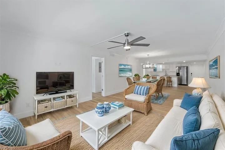 100 Estero BLVD #633_Living area featuring ceiling fan, light wood-style flooring, crown molding, and baseboards - virtually staged