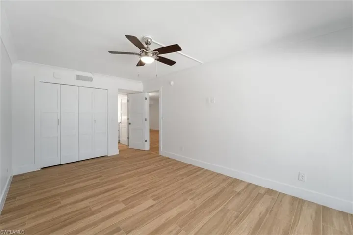 100 Estero BLVD #633_Unfurnished bedroom with light wood-style floors, baseboards, a closet, and a ceiling fan