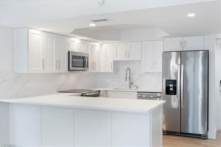 100 Estero BLVD #633_Kitchen with appliances with stainless steel finishes, a sink, a peninsula, white cabinetry, and recessed lighting