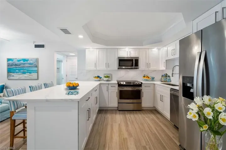 100 Estero BLVD #633_Virtually Staged -Kitchen featuring stainless steel appliances, a sink, a peninsula, light wood-style floors, and a breakfast bar