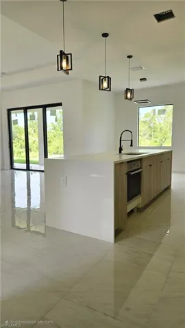 Kitchen featuring hanging light fixtures, light tile patterned floors, light stone counters, and open floor plan
