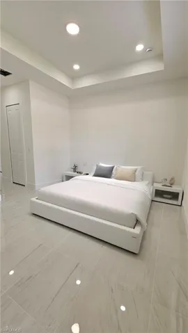 Bedroom featuring recessed lighting, a tray ceiling, and light tile patterned floors