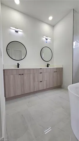 Full bath featuring a freestanding tub, double vanity, and recessed lighting
