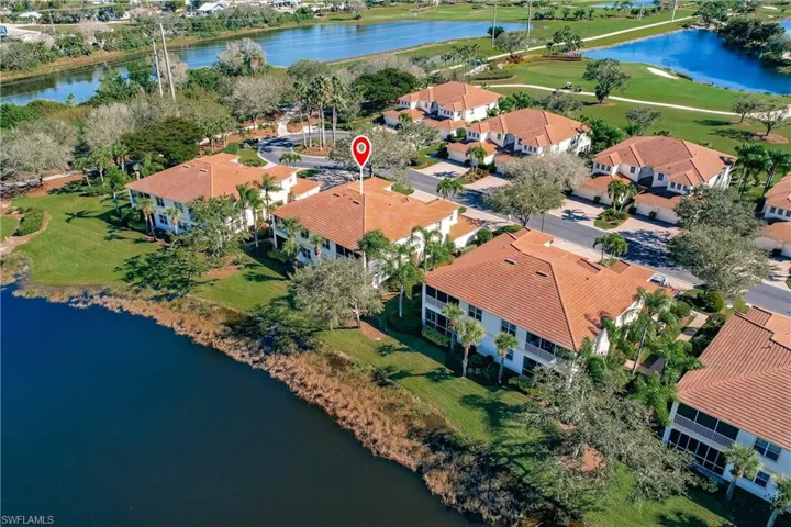 Tile roof residential structure situated alongside a body of water, featuring a screened lanai and surrounding green space