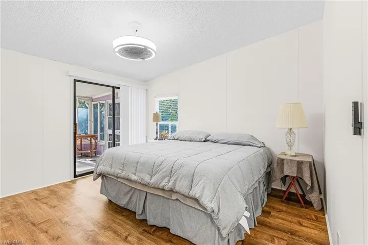 Bedroom featuring wood finished floors, access to outside, and a textured ceiling