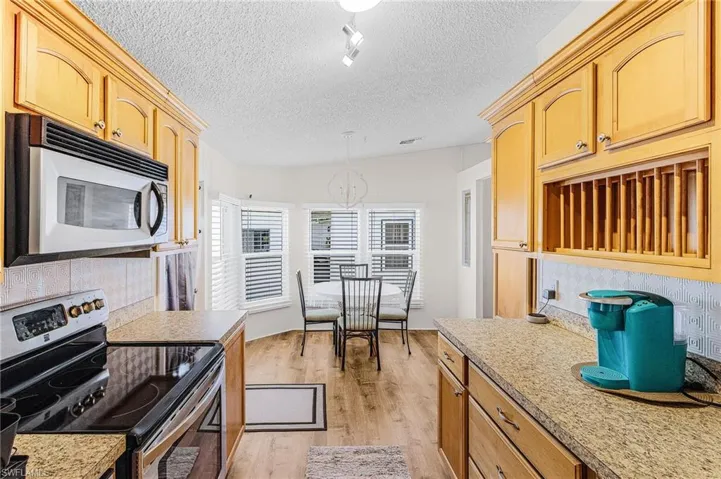 Kitchen featuring white microwave, electric stove, a chandelier, light wood-style floors, and a textured ceiling