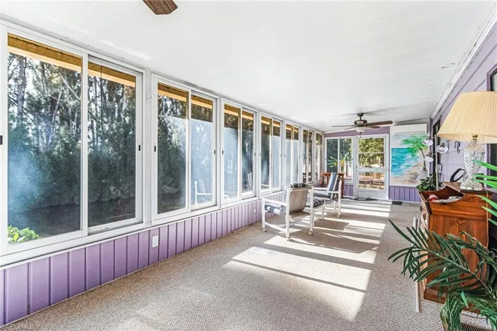 Sunroom / solarium featuring ceiling fan, healthy amount of natural light, and a wall mounted air conditioner